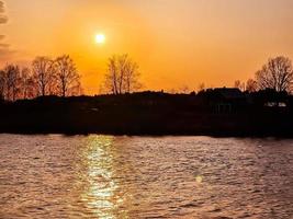 Sonnenuntergang über dem Fluss. Die Sonne spiegelt sich im Wasser. Pfad des Sonnenlichts. foto