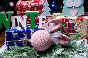 die inschrift winter von einem baum an einem neujahr. auf den fichtenzweigen vor dem hintergrund einer schneedecke befinden sich neujahrsblaue, weiße kugeln mit fichtenzapfen und eine schachtel mit einem geschenk. Weihnachten foto