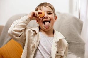 Porträt des kleinen entzückenden Jungen, der Keks hält. Kind mit Plätzchen. Kind und Gluten. Gesundheitswesen, Glutenunverträglichkeit bei Kindern. Vorschulkind mit Freizeitkleidung. Lächeln, positive Emotionen. foto