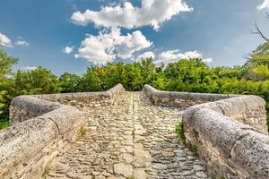 Felsensteinbrücke über kleinen Teich mit grünen Bäumen unter blauem Himmel. historische Landschaft, Idylle foto