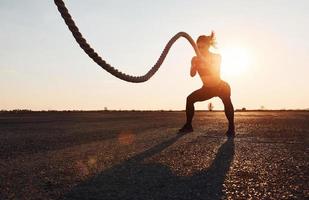 Frau im Sportbekleidungstraining mit Knoten auf der Straße zur Abendzeit foto