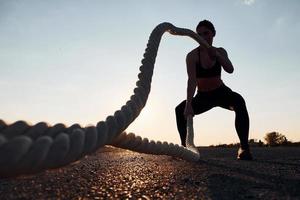 Frau im Sportbekleidungstraining mit Knoten auf der Straße zur Abendzeit foto