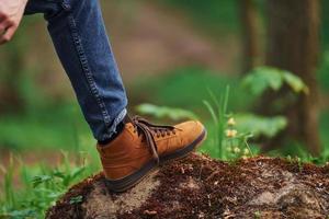 Nahaufnahme der Beine des Mannes auf dem Felsen im Wald. Reisende haben einen Spaziergang foto