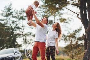 vater und mutter verbringen das wochenende im freien in der nähe des waldes mit der tochter foto