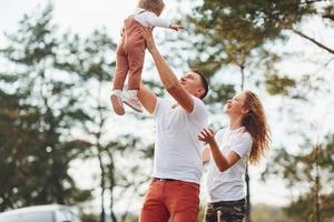 vater und mutter verbringen das wochenende im freien in der nähe des waldes mit der tochter foto