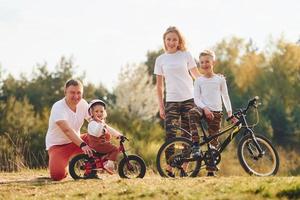 mit Fahrrädern. glückliche familie, die zusammen ein wochenende im freien in der nähe des waldes verbringt. mit Tochter und Sohn foto