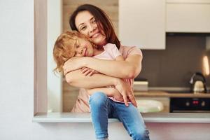 auf der Küche. junge mutter mit ihrer kleinen tochter in lässiger kleidung zusammen zuhause zu hause foto