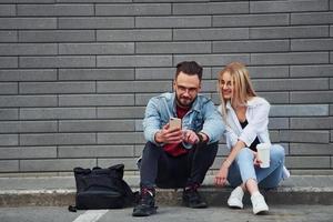 junger stilvoller mann mit frau in lässiger kleidung, die zusammen im freien sitzt. Vorstellung von Freundschaft oder Beziehungen foto