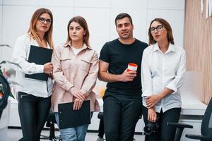 Gruppe von Geschäftsleuten in formeller Kleidung, die zusammen drinnen im Büro stehen foto