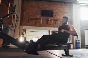 starker afroamerikanischer mann in sportlicher kleidung hat einen trainingstag im fitnessstudio mit geräten foto