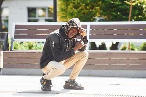 junger afrikanisch-amerikanischer Mann in schwarzer Jacke im Freien in der Stadt foto