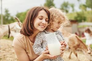 frische natürliche Milch. junge mutter mit ihrer tochter ist im sommer auf dem bauernhof foto