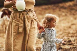 frische natürliche Milch. junge mutter mit ihrer tochter ist im sommer auf dem bauernhof foto