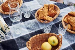 Blick von oben auf den Picknicktisch mit Äpfeln, Süßigkeiten und leeren Gläsern darauf foto