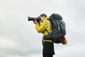junger männlicher fotograf mit seiner professionellen kamera, die bilder von schöner natur macht foto