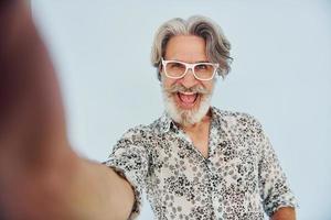 tourist macht selfie. älterer stilvoller moderner mann mit grauem haar und bart zuhause foto