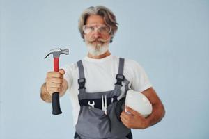 Handwerker bereit für die Arbeit. älterer stilvoller moderner mann mit grauem haar und bart zuhause foto