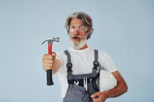 Handwerker bereit für die Arbeit. älterer stilvoller moderner mann mit grauem haar und bart zuhause foto