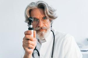 Das Porträt eines leitenden männlichen Arztes mit grauem Haar und Bart im weißen Mantel befindet sich in der Klinik für Hals-Nasen-Ohrenheilkunde foto