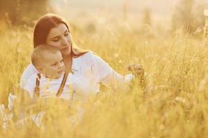 junge mutter mit ihrem kleinen sohn ist draußen auf dem landwirtschaftlichen gebiet. schöner Sonnenschein foto