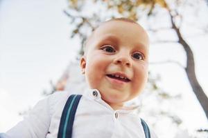 Porträt eines glücklichen kleinen Jungen, der im Freien steht und in die Kamera lächelt foto