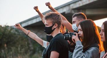 Fotograf mit Kamera. Gruppe protestierender junger Menschen, die zusammenstehen. Aktivist für Menschenrechte oder gegen die Regierung foto