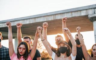 hoch erhobene Fäuste. Gruppe protestierender junger Menschen, die zusammenstehen. Aktivist für Menschenrechte oder gegen die Regierung foto