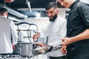 menschen in weißer uniform kochen zusammen in der küche. arbeitsreicher Tag foto