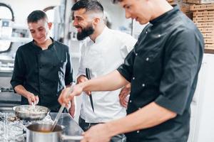 gruppe von menschen, die zusammen essen in der küche kochen. arbeitsreicher Tag foto