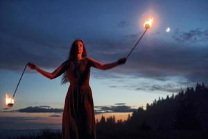 Feuershow von Frau im Kleid in den nächtlichen Karpaten. schöne Landschaft foto