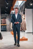 Einkaufstag. junger mann im modernen geschäft mit neuen kleidern. elegante teure kleidung für männer foto
