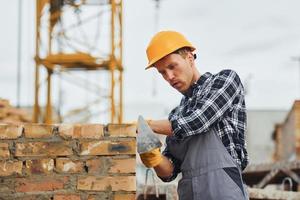 Ziegel legen. bauarbeiter in uniform und sicherheitsausrüstung haben arbeit am bau foto