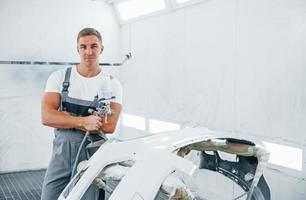 mit Lackierpistole. kaukasischer automechaniker in uniform arbeitet in der garage foto