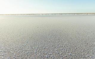 weißer Sand an der Küste. Brücke ist weit entfernt im Hintergrund foto