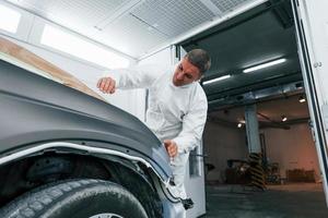 Auto mit braunem Tuch abdecken. kaukasischer automechaniker in uniform arbeitet in der garage foto