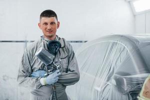 kaukasischer automechaniker in uniform arbeitet in der garage foto