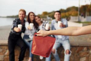 Rote Packung Kaffee. Gruppe junger, fröhlicher Freunde, die draußen Spaß haben foto