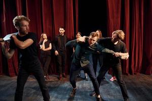 Kampfszene. Gruppe von Schauspielern in dunkler Kleidung bei der Probe im Theater foto