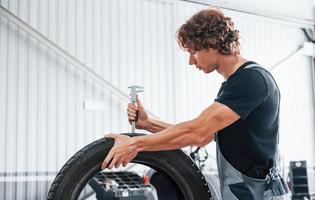 funktioniert mit Reifen. erwachsener mann in grauer uniform ist im autosalon foto