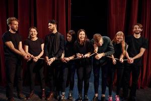 mit Seil in den Händen. Gruppe von Schauspielern in dunkler Kleidung bei der Probe im Theater foto