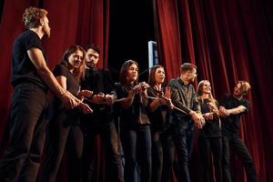 Knoten in den Händen. Gruppe von Schauspielern in dunkler Kleidung bei der Probe im Theater foto