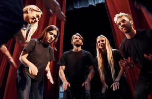 vor roten Vorhängen stehen. Gruppe von Schauspielern in dunkler Kleidung bei der Probe im Theater foto