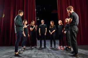 zusammen arbeiten. Gruppe von Schauspielern in dunkler Kleidung bei der Probe im Theater foto