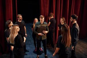 Praxis im Gange. Gruppe von Schauspielern in dunkler Kleidung bei der Probe im Theater foto