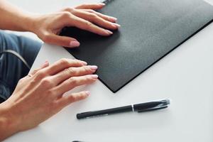 Die Hände der Frau halten einen schwarzen Notizblock, der auf dem Tisch liegt foto