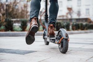 Nahaufnahme eines Mannes, der tagsüber mit einem Elektroroller im Freien in der Stadt fährt foto