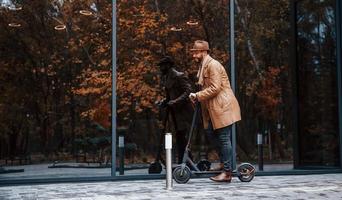 Elektroroller fahren. junges männliches model in modischer kleidung ist tagsüber draußen in der stadt foto