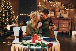 selfie machen mit dem telefon. junge schöne paare haben zusammen ein romantisches abendessen drinnen foto