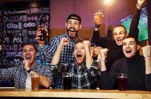 Fußballfans, die fernsehen. gruppe von menschen zusammen drinnen in der kneipe haben spaß am wochenende foto