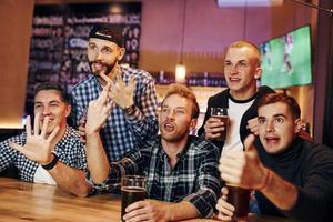 Fußballfans, die fernsehen. gruppe von menschen zusammen drinnen in der kneipe haben spaß am wochenende foto